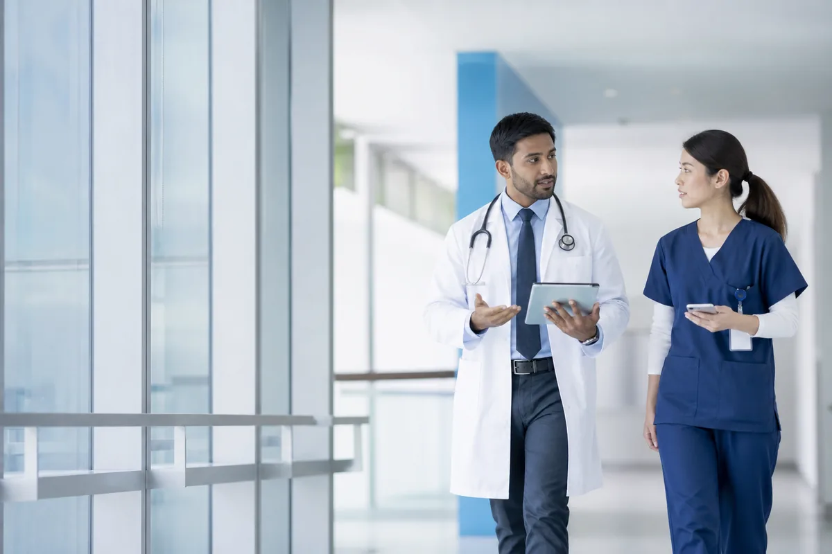 Physician and nurse walking together through a hospital corridor